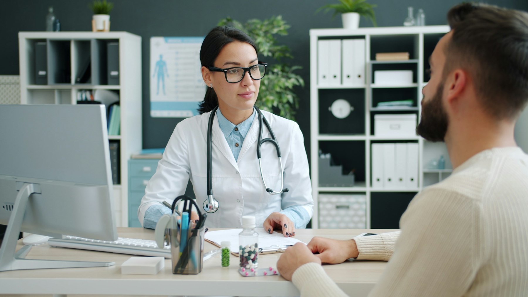 A physician in a white coat talking with a patient in a bright office