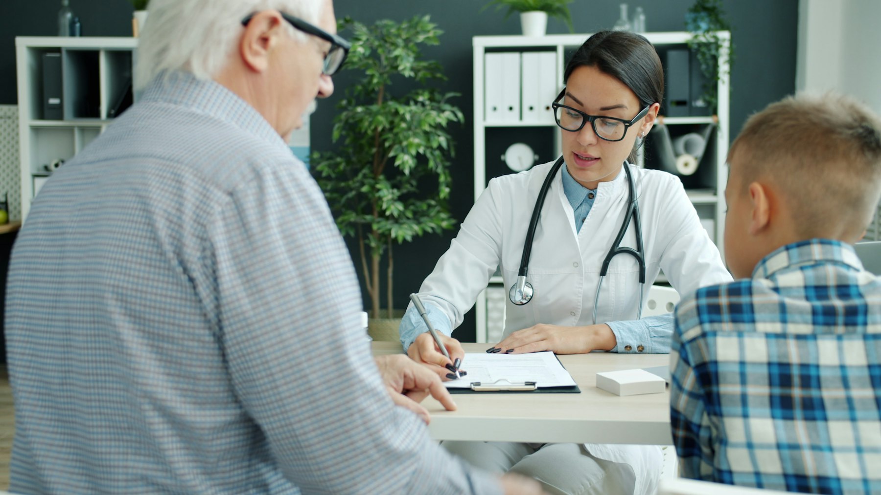 A family medicine clinician meeting with an older man and a young boy